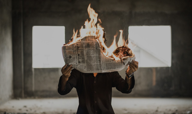 燃える新聞を持つ人物